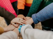 group stacking hands in colorful sweaters